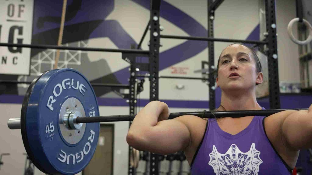 A woman holding a barbell in the front rack position