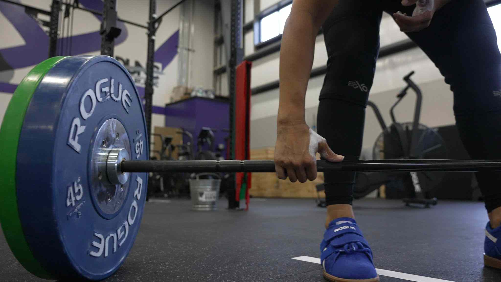 a woman grabbing a barbell in preparation for a lift