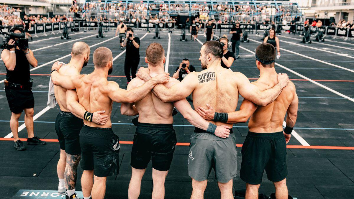 A group of five shirtless people standing in front of cameras.