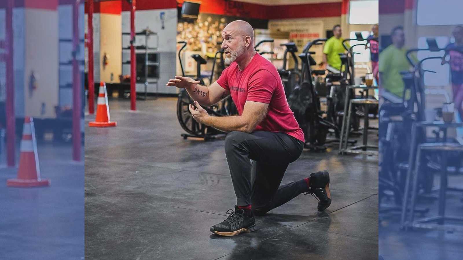A man takes a knee while instructing a course