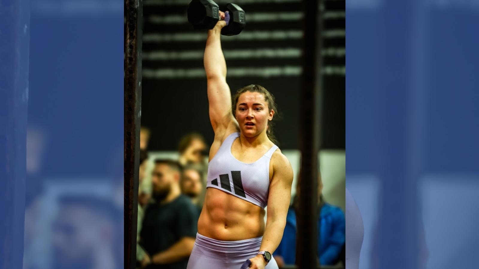 Jennifer Muir triumphantly holds up a dumbbell.